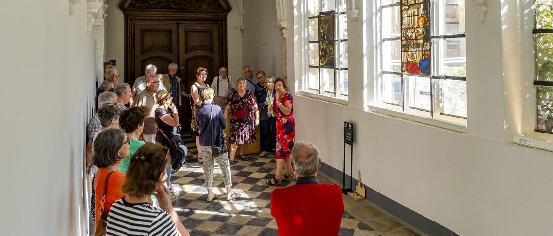 Een groep kijkt naar glasramen in de pandgang