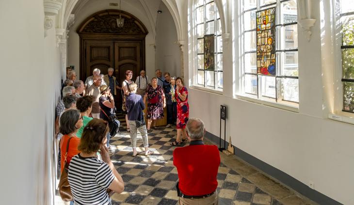 Een groep kijkt naar glasramen in de pandgang